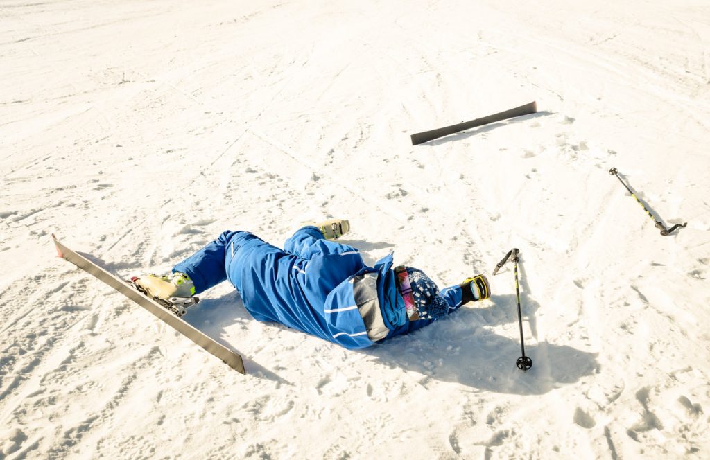 Jazda na nartach - narciarz leżący na śniegu po upadku.